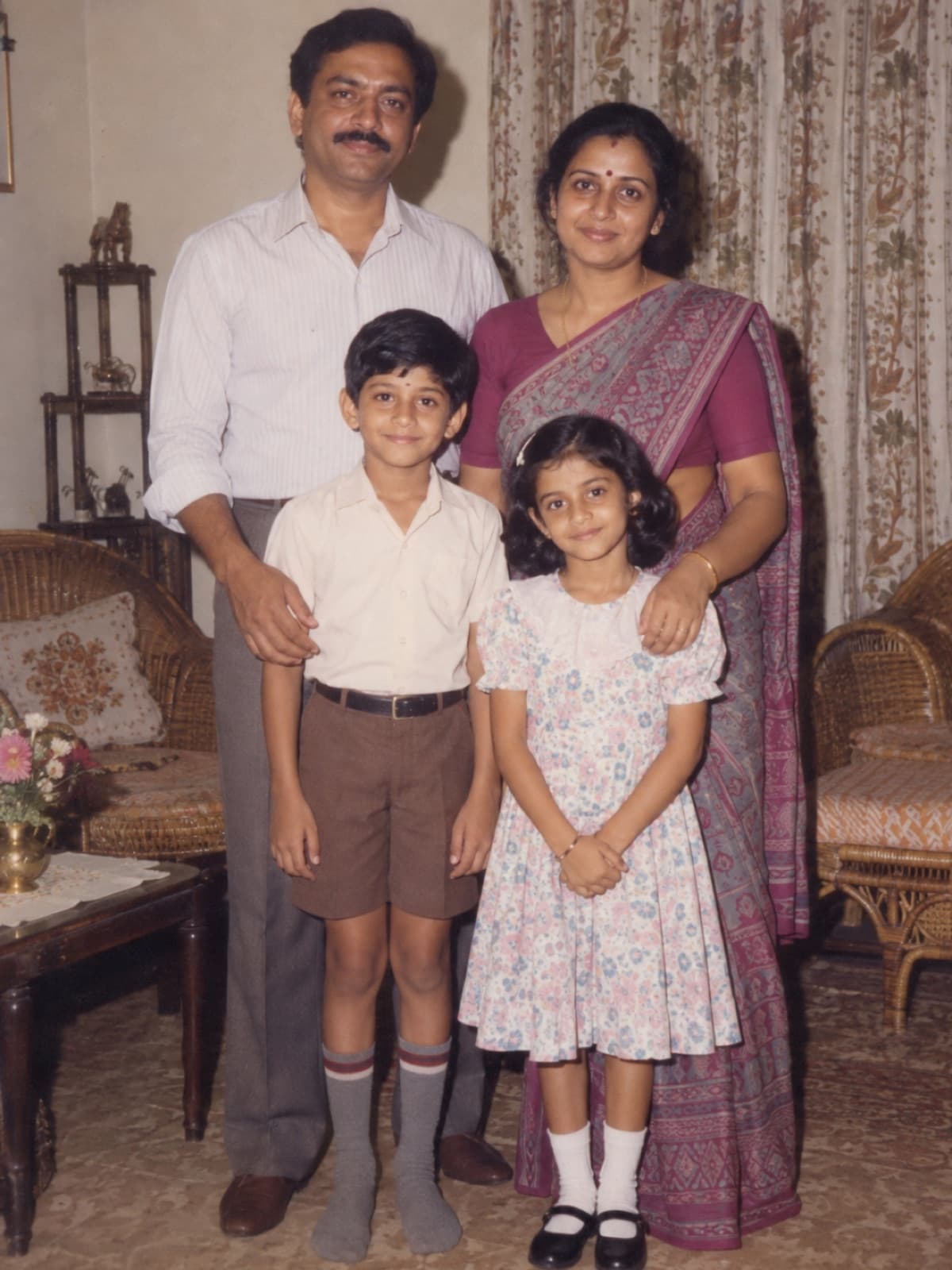 AI-generated example of a four-person South Asian family photographed with direct flash in a mid-1980s living room